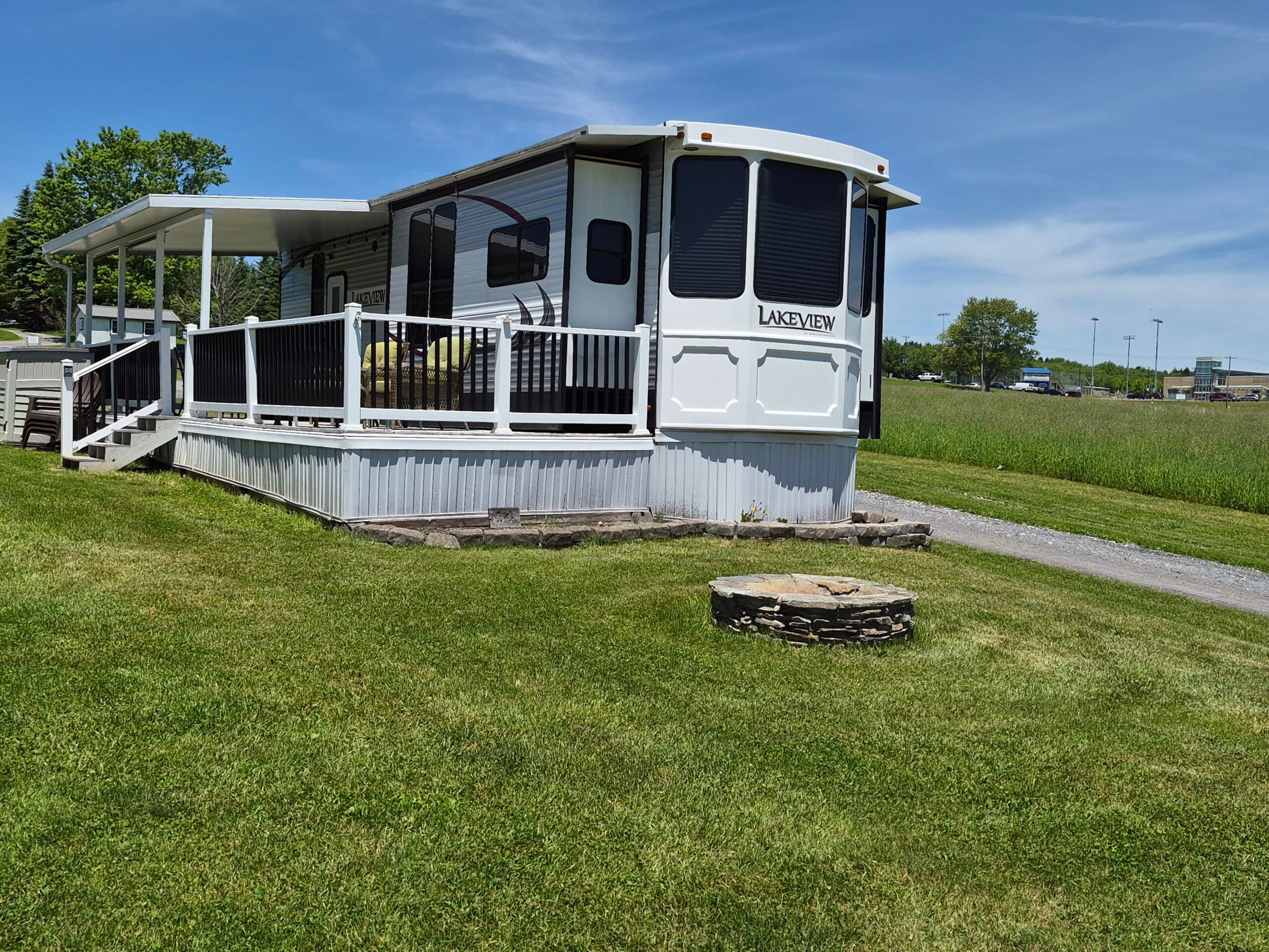 Outside of Camper shows deck, awning and firepit.