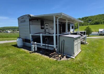 Back side of Camper showing deck, small shed, and LP tank.