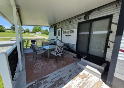 On the deck, shows patio table with four chairs and view off back of camper.