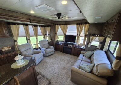 From Kitchen, shows living room with two recliner chairs, pull out love seat and television.