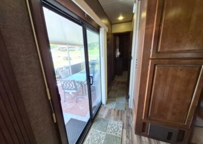 Image from kitchen looking past the main sliding glass door, shows the hallway to the bedroom and bathroom.