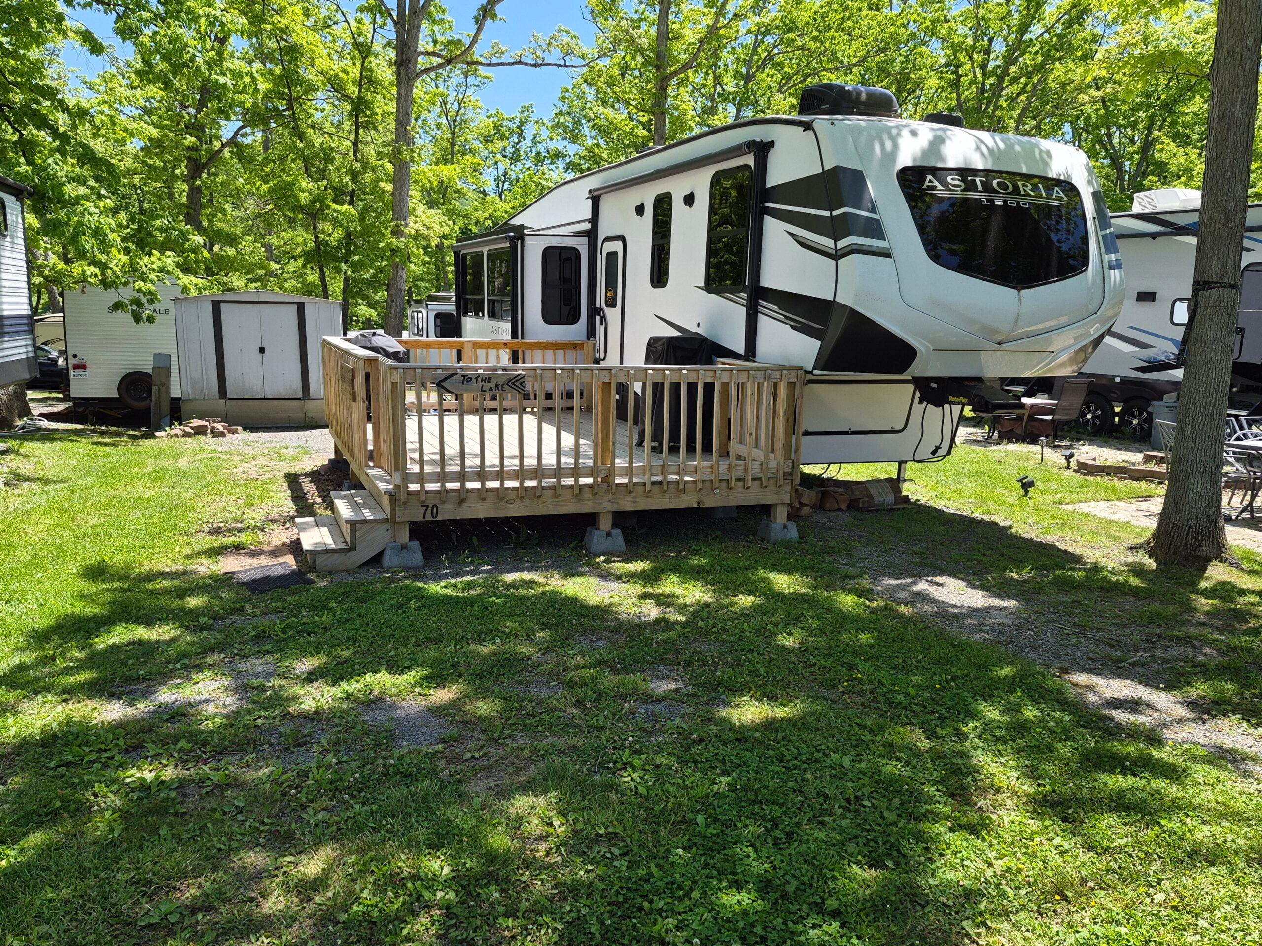 Exterior photo of camper shows deck and shed.