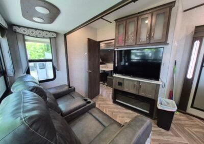 Image of Living Area shows two reclining seats, television and entry to Bunkhouse.