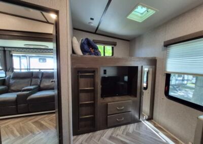 Image of bunkhouse shows bunk bed over storage and tv nook.