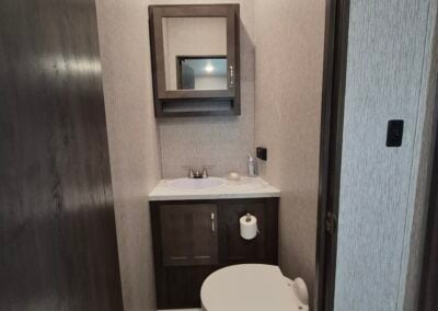 Image of bunkhouse half bath shows sink, toilet and cabinet.