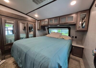 Image of main bedroom shows queen bed, overhead cabinets and full closet.