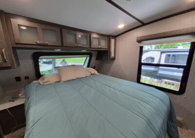 Image of Main Bedroom shows Queen Bed and overhead cabinets.