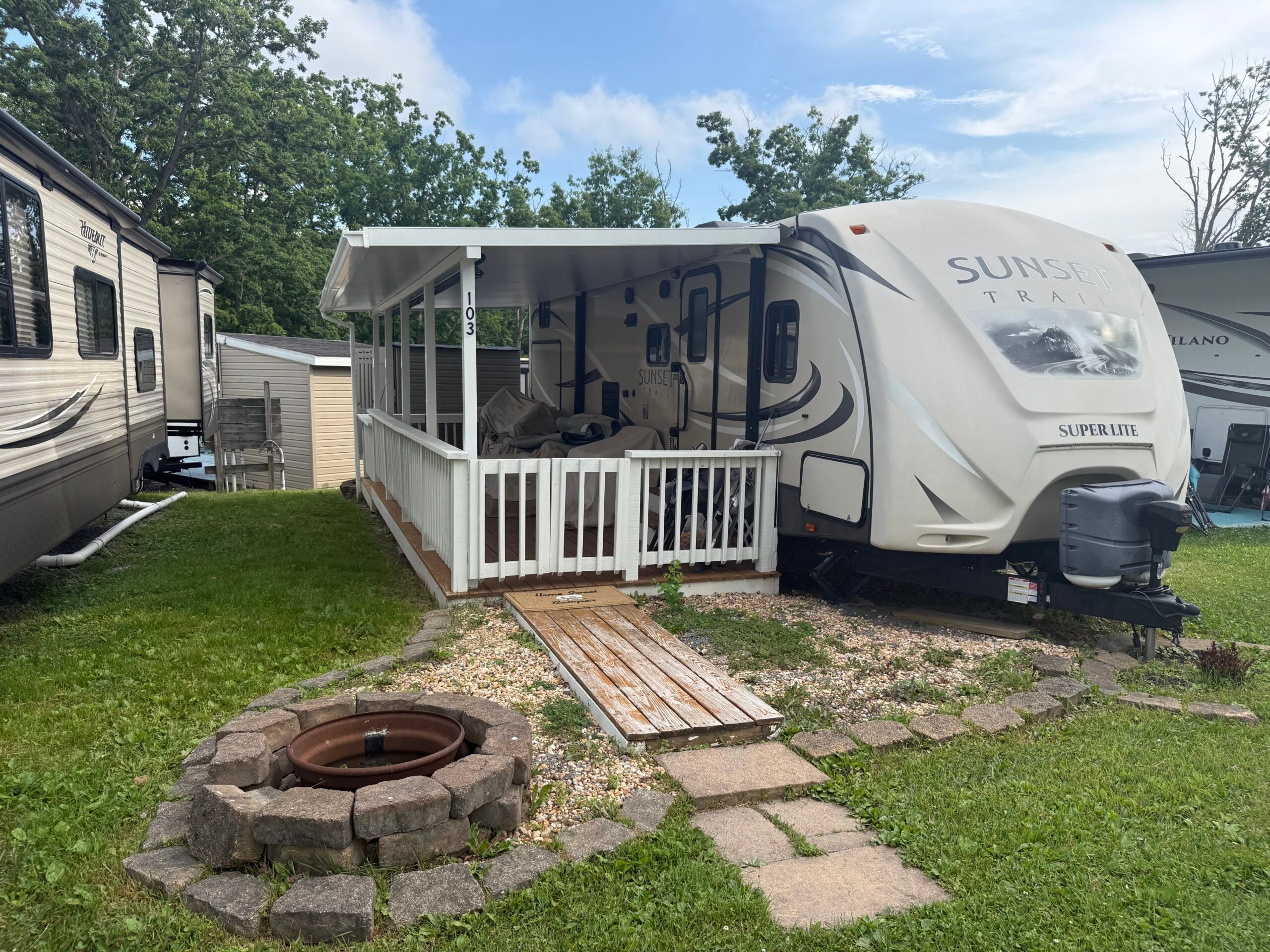 outside of camper and fire pit with deck and hard awning